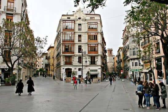Vista panorámica de la Plaza de los Fueros con edificios históricos y peatones caminando