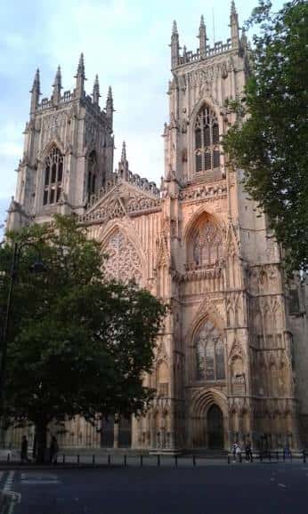 Vista frontal de la Catedral de York con árboles en primer plano y cielo despejado