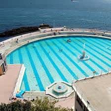 Piscina exterior del Tinside Lido con personas nadando y vista al océano