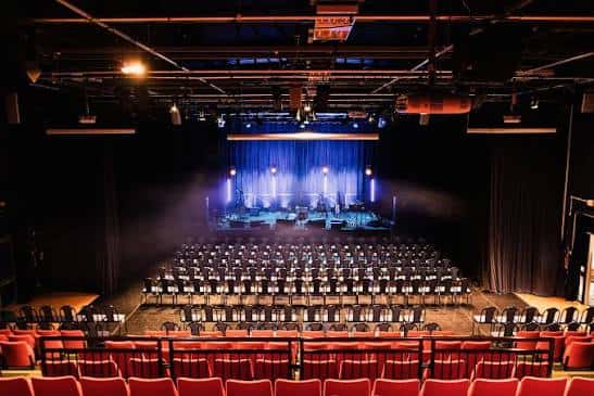 Vista general del auditorio del Barbican Theatre con butacas rojas y escenario iluminado