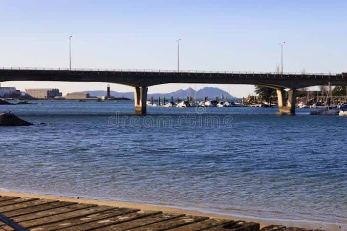 Puente de Bouzas sobre el agua con puerto deportivo y montañas en el horizonte