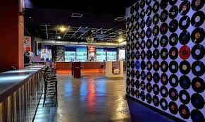 Interior del Loco Club mostrando barra, suelo brillante y pared decorada con vinilos