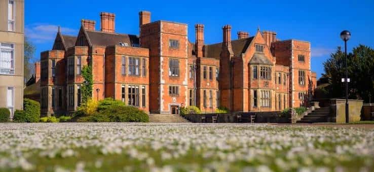 Edificio de ladrillo rojo de la Universidad de York con jardín de flores blancas en primer plano