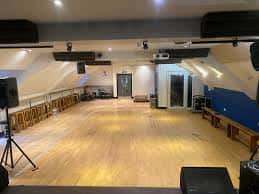 Gran sala de baile con suelo de madera y equipo de sonido