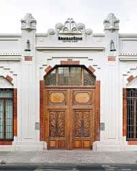 Vista exterior de la entrada principal de Bombas Gens con su fachada neoclásica y puerta de madera