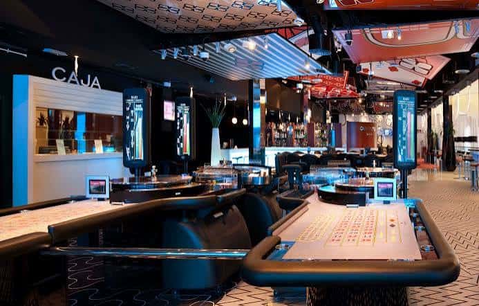 Interior del casino con mesas de juego y zona de bar