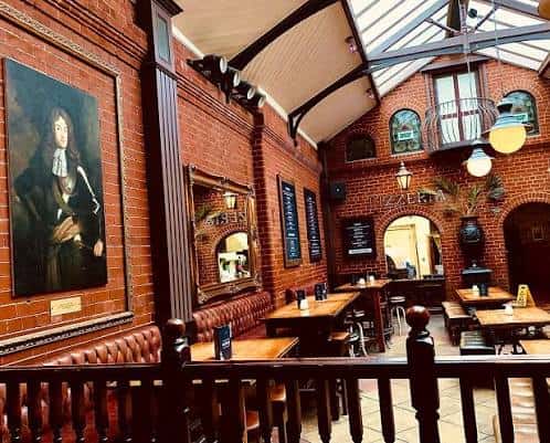 Vista del interior del pub con paredes de ladrillo, mesas y decoración clásica