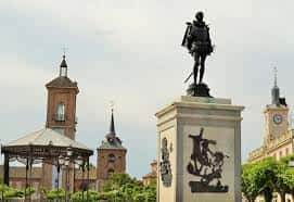 Detalle de la estatua de Miguel de Cervantes con las torres de la Universidad de Alcalá al fondo