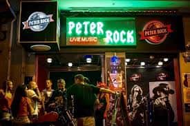 Fachada exterior del Peter Rock Club por la noche con letrero luminoso verde