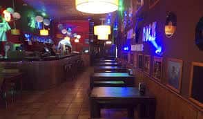 Interior del bar con mesas, barra y decoración temática de rock
