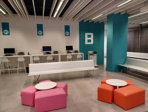 Área de espera con mobiliario colorido y mostradores de atención