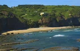 Playa de Peñarrubia rodeada de vegetación y acantilados verdes