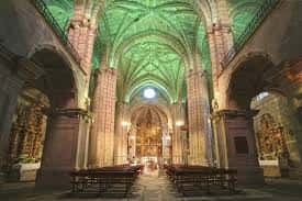 Interior de la iglesia del monasterio con bóvedas góticas iluminadas