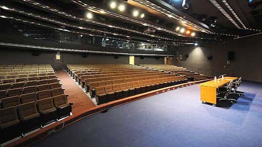 Interior del auditorio con disposición de mesas y butacas para eventos