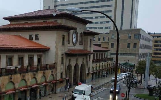 Fachada principal de la Estación del Norte con reloj central y edificios modernos al fondo en día nublado