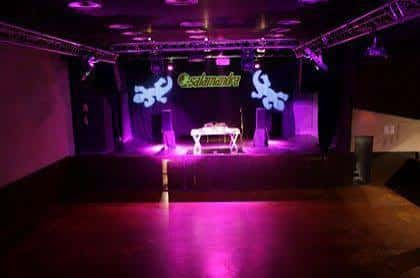 Escenario vacío de la sala Salamandra con iluminación púrpura y logotipo proyectado
