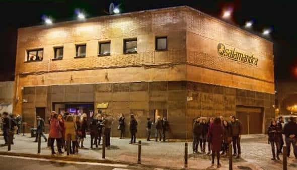 Fachada exterior nocturna de la sala Salamandra en L'Hospitalet con cola de asistentes
