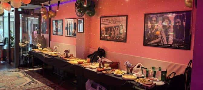 Mesa de buffet en el Pub Ñoña con decoración de globos y murales de músicos en la pared