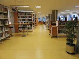 Pasillo central de la biblioteca con estanterías y suelo amarillo