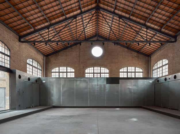 Interior del espacio principal con techo de vigas metálicas y paredes de ladrillo