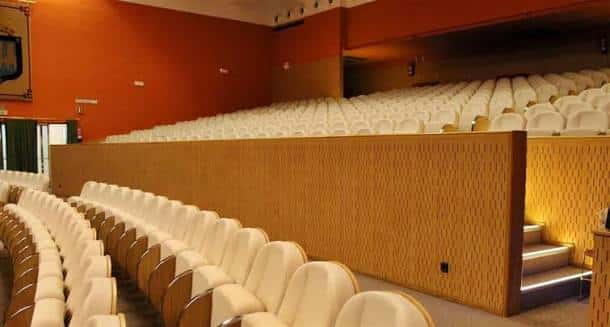 Interior del auditorio con butacas blancas y paredes en tonos cálidos