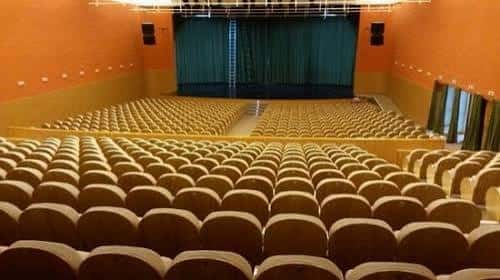 Aula de espectáculos con cortinas verdes y butacas dispuestas en gradas