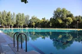 Piscina al aire libre con escalera de acceso y reflejos del cielo en el agua