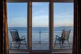 Vista al mar desde una habitación con balcón y sillas