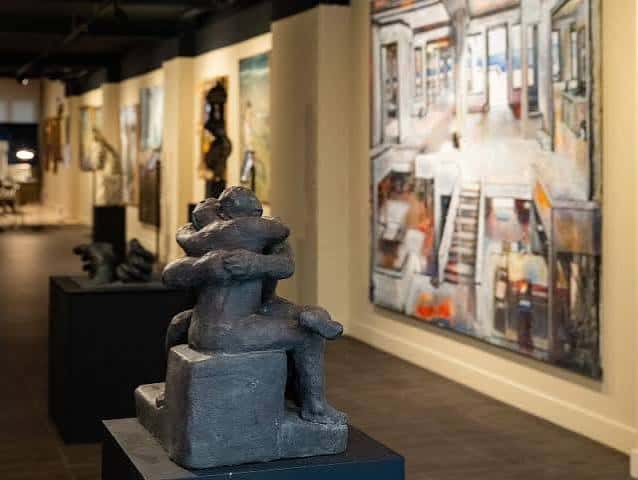 Escultura de bronce en primer plano con pinturas al fondo
