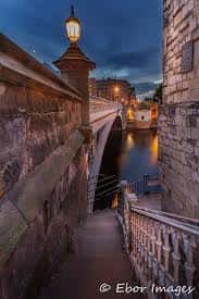Escaleras de piedra que descienden hacia el río desde un puente histórico en York