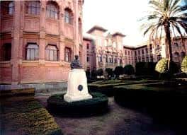 Jardín interior del Rectorado con estatua y palmeras, mostrando el entorno del edificio