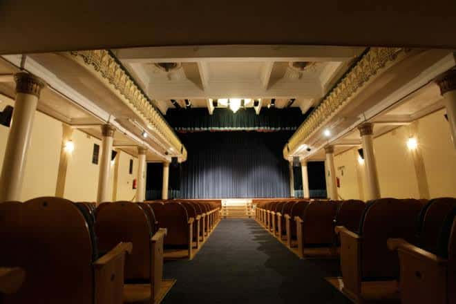 Vista frontal del auditorio con cortina negra y columnas ornamentadas