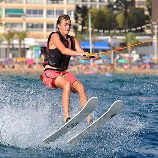 Joven practicando wakeboard con esquís acuáticos en aguas turquesas