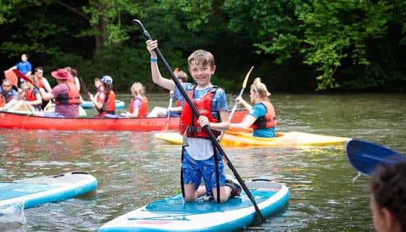 Actividad acuática con niños en paddleboard y canoas en el río