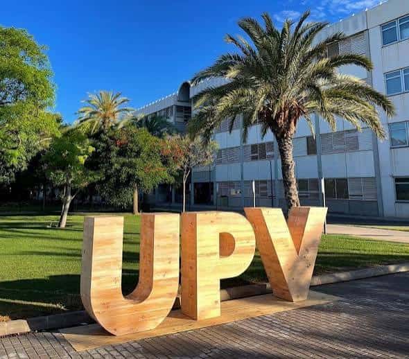 Letras gigantes de madera con las siglas UPV en el jardín del campus