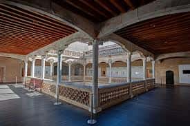Vista del patio interior con galería de arcos y suelo de baldosas oscuras