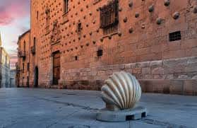Detalle de la fachada de la Casa de las Conchas con una gran concha escultórica en primer plano al atardecer
