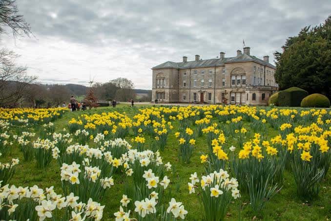 Vista panorámica de la fachada principal de Sledmere House rodeada de jardines con flores de primavera