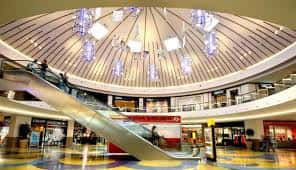 Vista interior del atrio principal del Centro Comercial Área Sur con escaleras mecánicas y techo abovedado