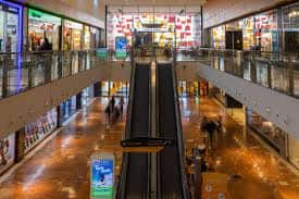 Pasillo central del centro comercial con tiendas iluminadas y escaleras en perspectiva