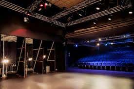 Escenario vacío con estructura de luces y butacas al fondo