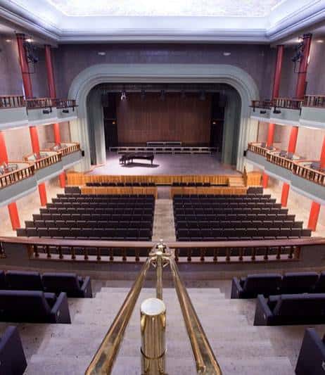 Vista panorámica del interior del Paraninfo con escenario, piano y butacas