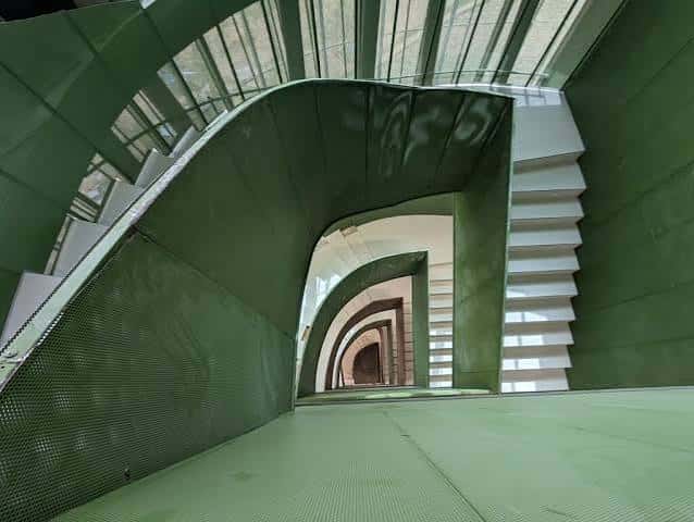 Escalera interior con estructura curva y revestimiento verde metálico