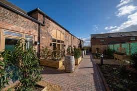 Patio exterior de Goose Beck Vineyard con jardines y barriles decorativos