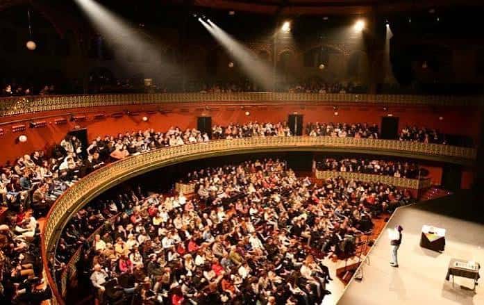 Auditorio lleno durante un evento con iluminación escénica