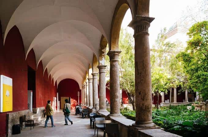 Galería de arcos con columnas de piedra y jardín central