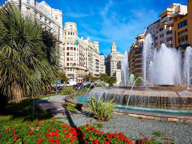 Detalle de la fuente y jardines de la plaza con edificios de fondo