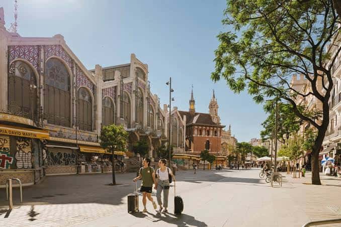 Vista exterior de la Plaza del Mercado de Valencia con su arquitectura modernista y turistas caminando