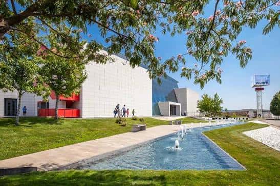Exterior del museo con jardín, fuente y visitantes caminando por el sendero