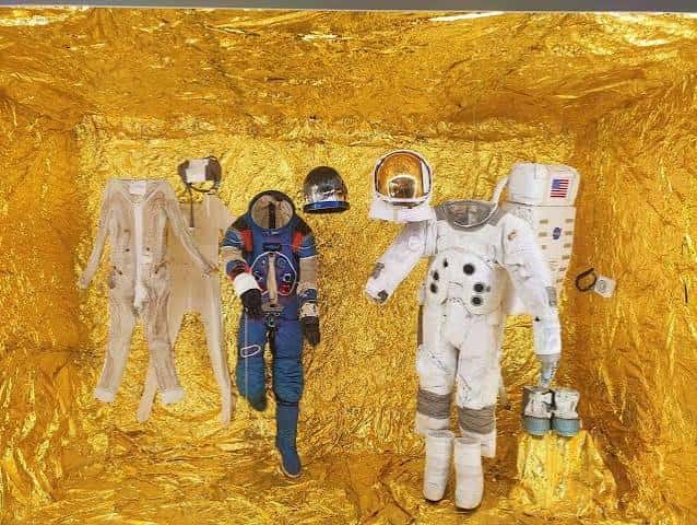 Exposición de trajes espaciales en una habitación con revestimiento dorado